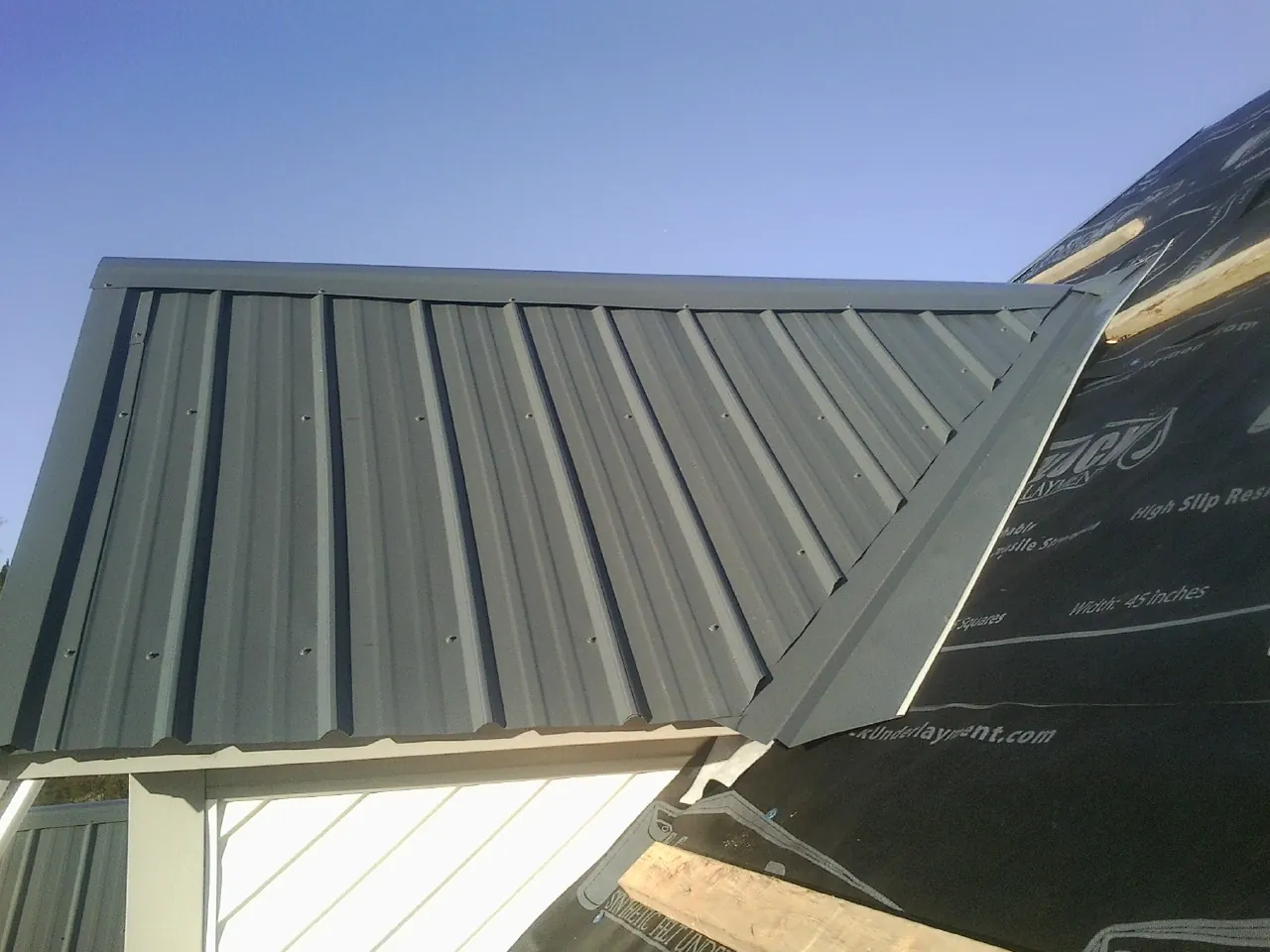 Gray metal roof panels going on over a garage gable in Cove