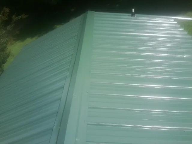 New green metal panels meeting at the ridge of a roof — Flat Roof Repair work by our crew in Cove