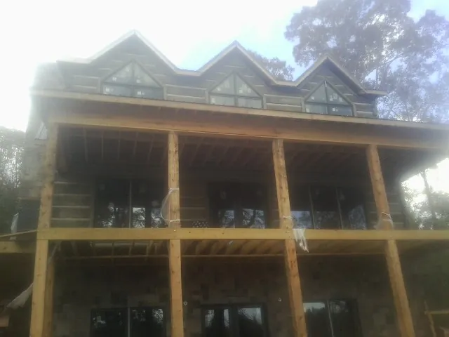 Dormers and porch framing on a large log home under construction — Roof Coating work by our crew in Cove