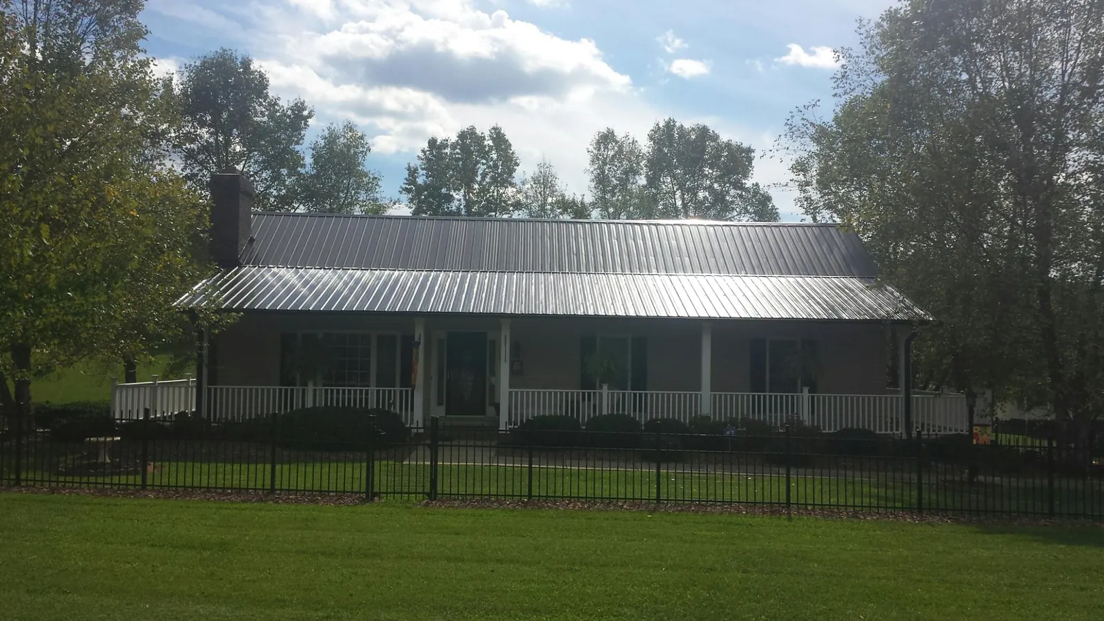 Gray metal roof on a brick ranch with a full width front porch — Gutter Guard Installation work by our crew in Cove