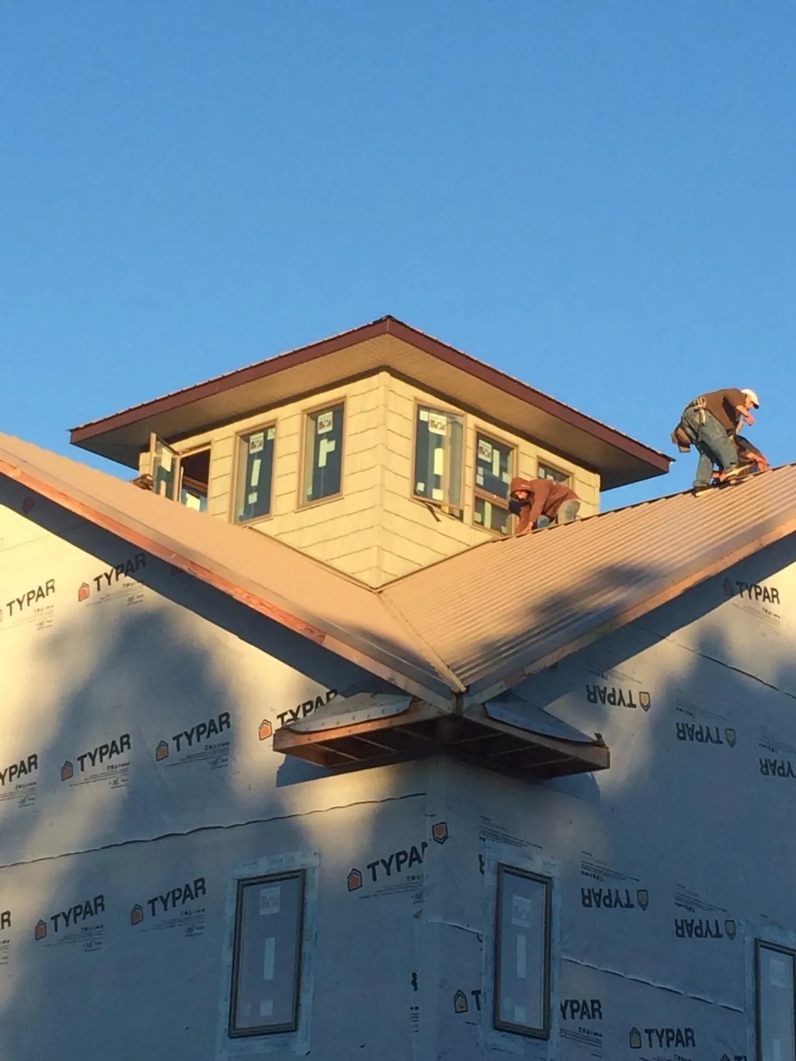 Roofers working around a rooftop cupola on a new metal roof at sunset — Roof Waterproofing in Cove by Roofing Brothers